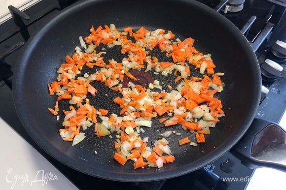 Оставшуюся половинку лука вместе с чесноком и морковкой мелко нарезать. Разогрейте на сковороде растительное масло и обжарьте на нем нарезанный лук (примерно 2–3 минуты). Добавьте к луку морковь и чеснок, перемешайте и обжаривайте еще 2 минуты.